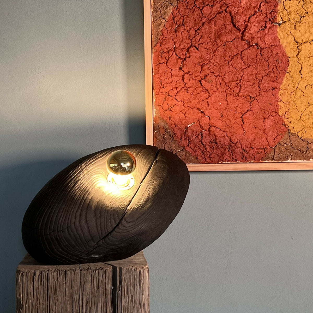 Galet lumineux sur socle en bois, lumière LED dorée.