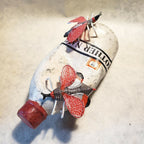 Sculpture de bouteille blanche chapeau rouge, papillons rouges et ruban noir autour