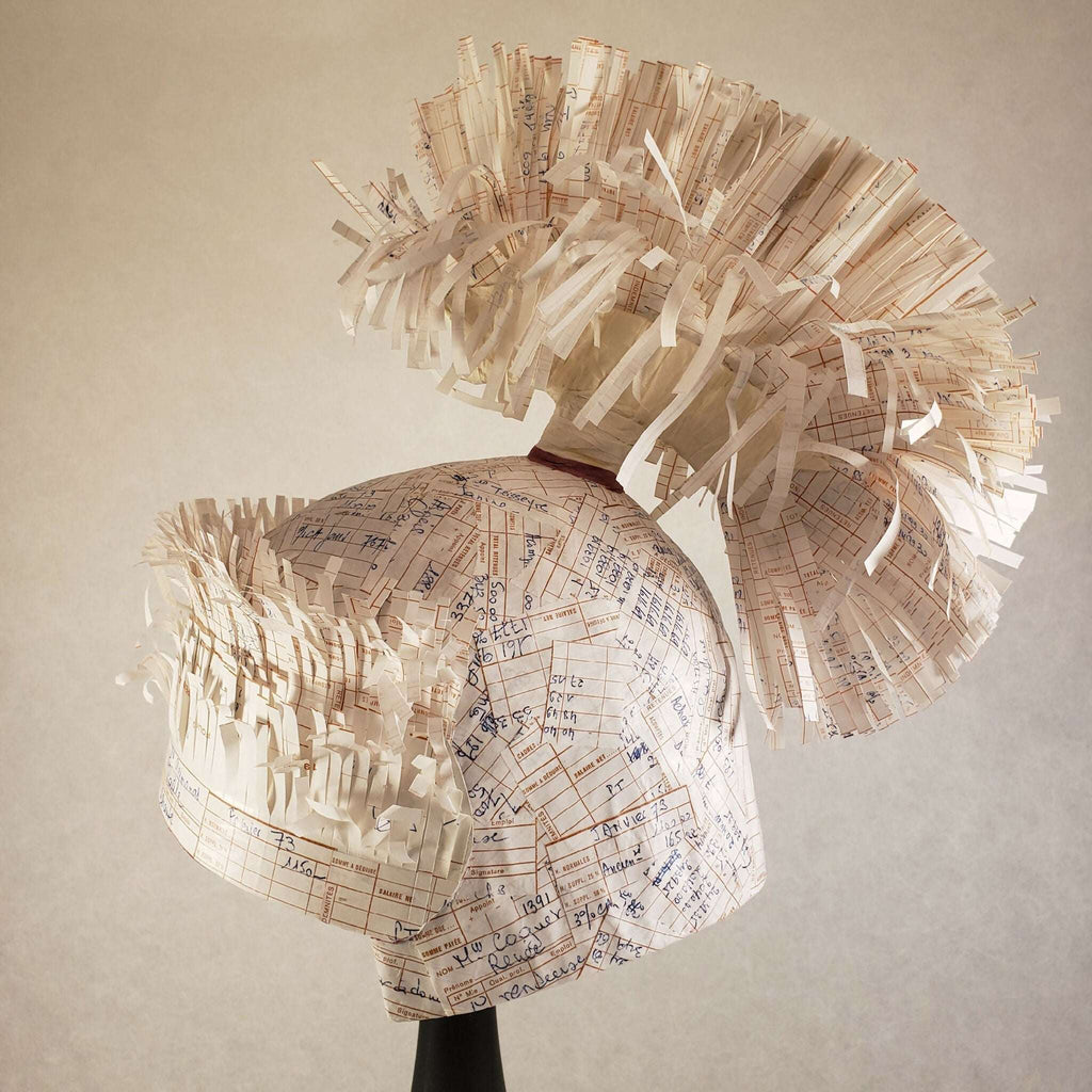 Casque à aigrette en papier imprimé beige, vue de dessus sur mannequin, franges visibles.
