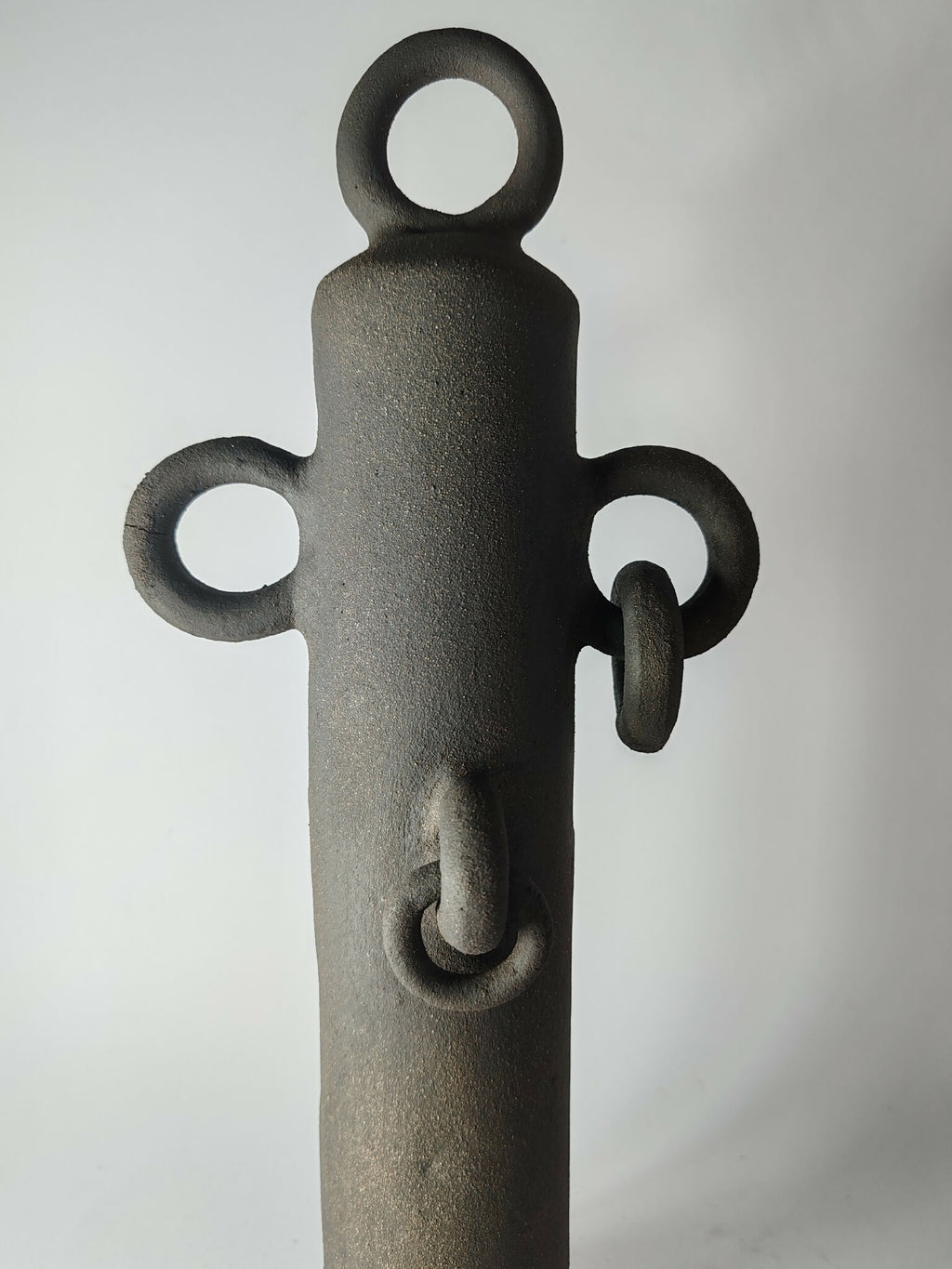 Sculpture totem noir avec anneau supérieur, deux anses latérales et motif central