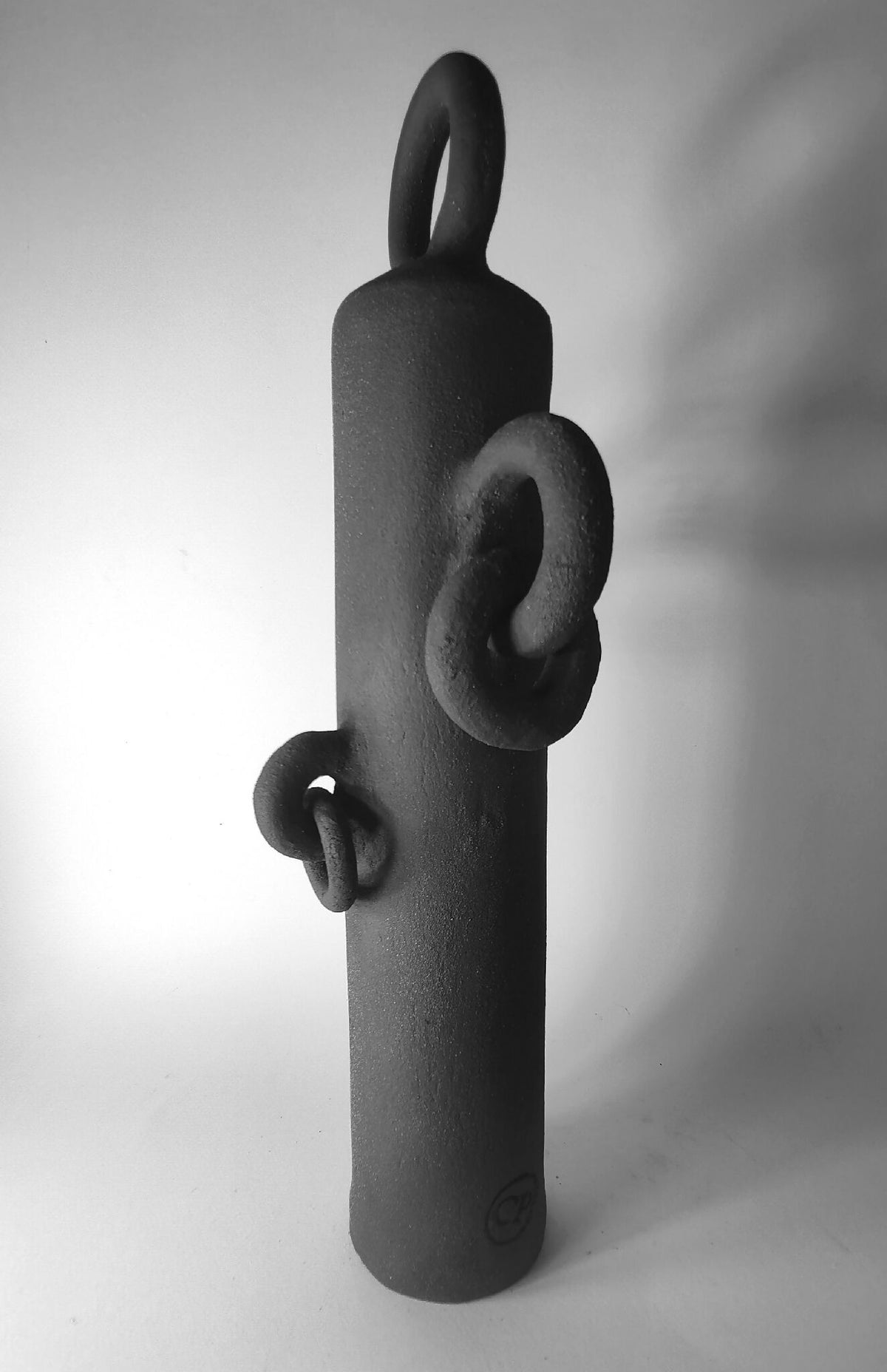 Sculpture totem noir vue de côté avec anneau supérieur et anses en relief