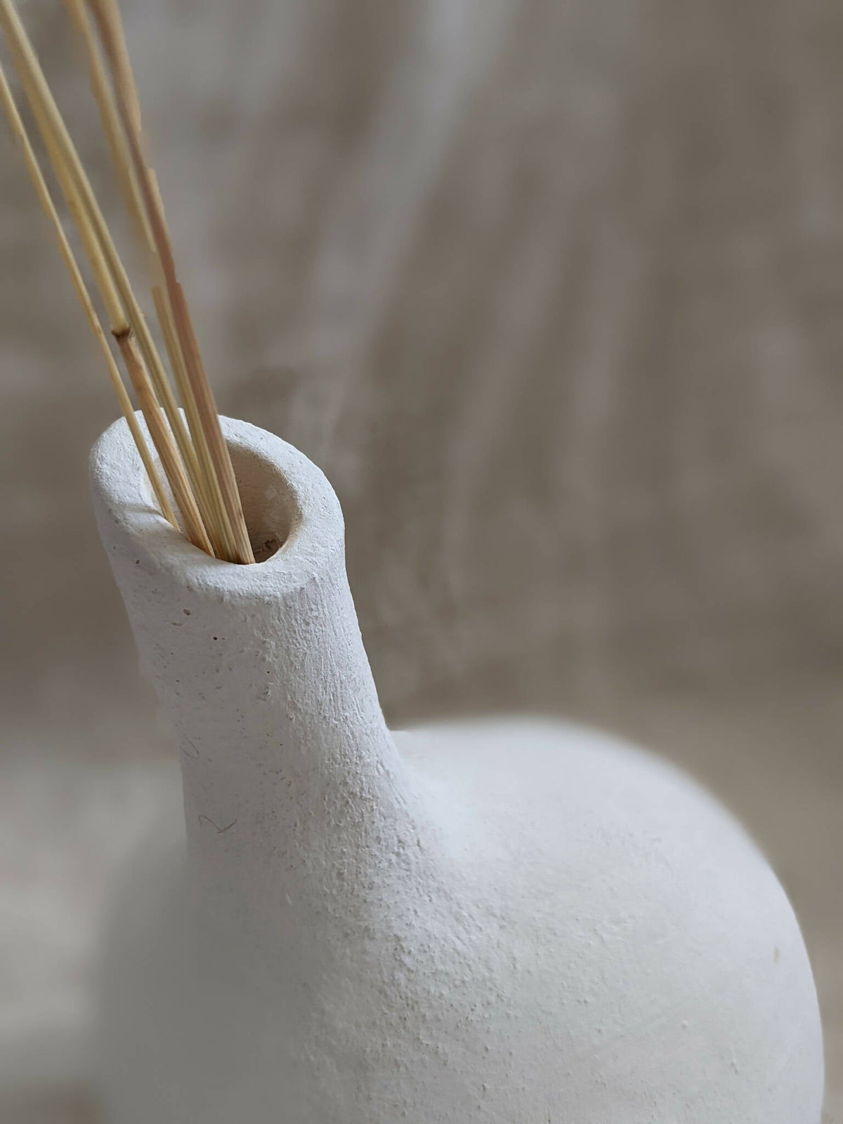 Vase sculpture bulbe blanc avec tiges sèches dans l’ouverture