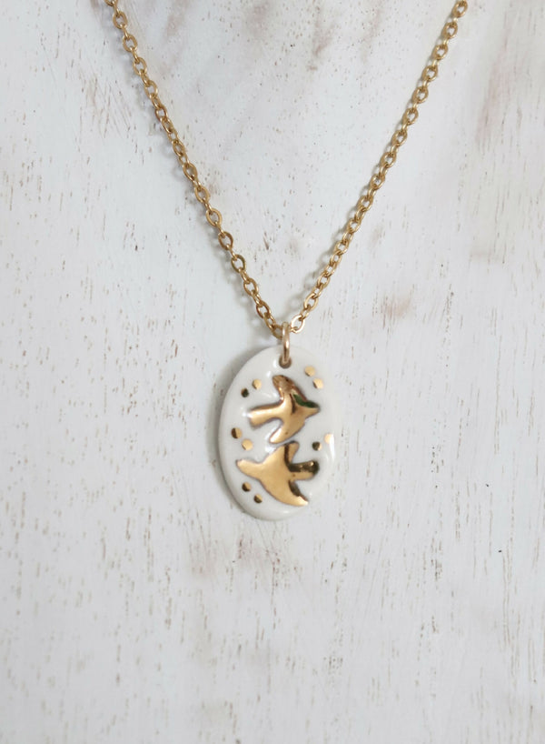 Collier en porcelaine avec médaillon ovale blanc et hirondelles dorées, chaîne dorée