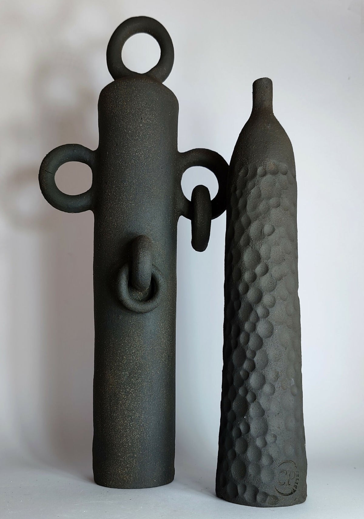 Ensemble de soliflores sculptés noirs : une pièce à anses et une bouteille à relief.