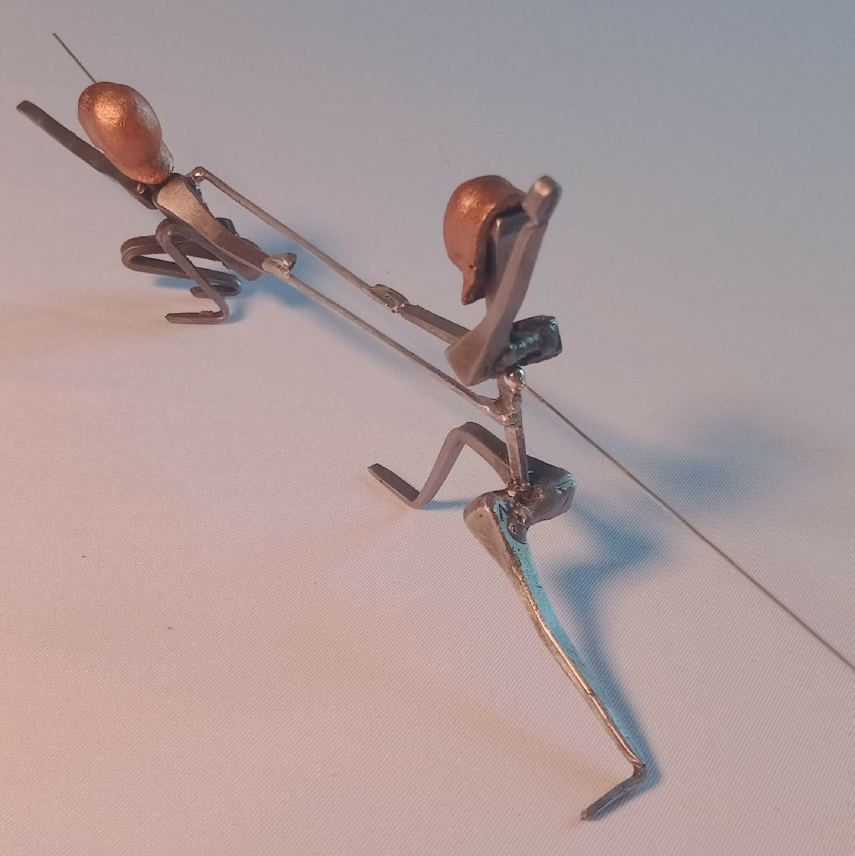 Deux statuettes d’escrimeuses en acier, une en extension haute, une en appui, têtes cuivre.