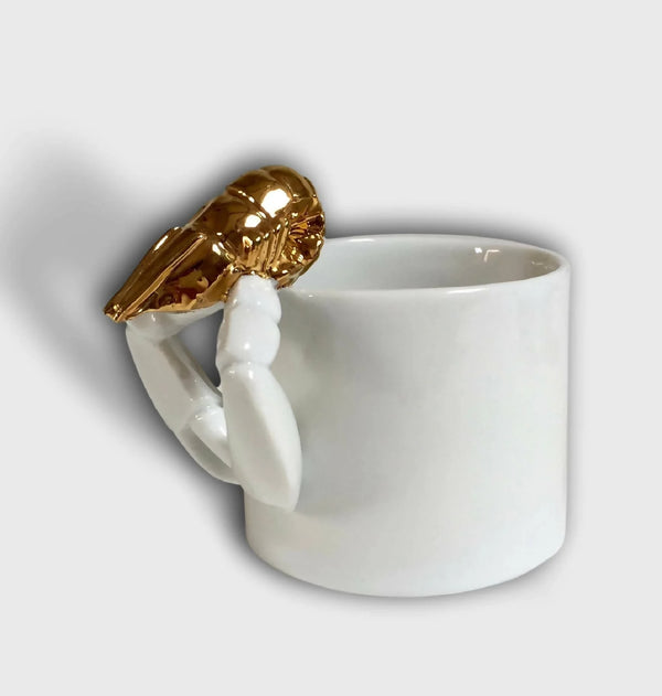 Tasse blanche avec figurine de homard doré sur l’anse