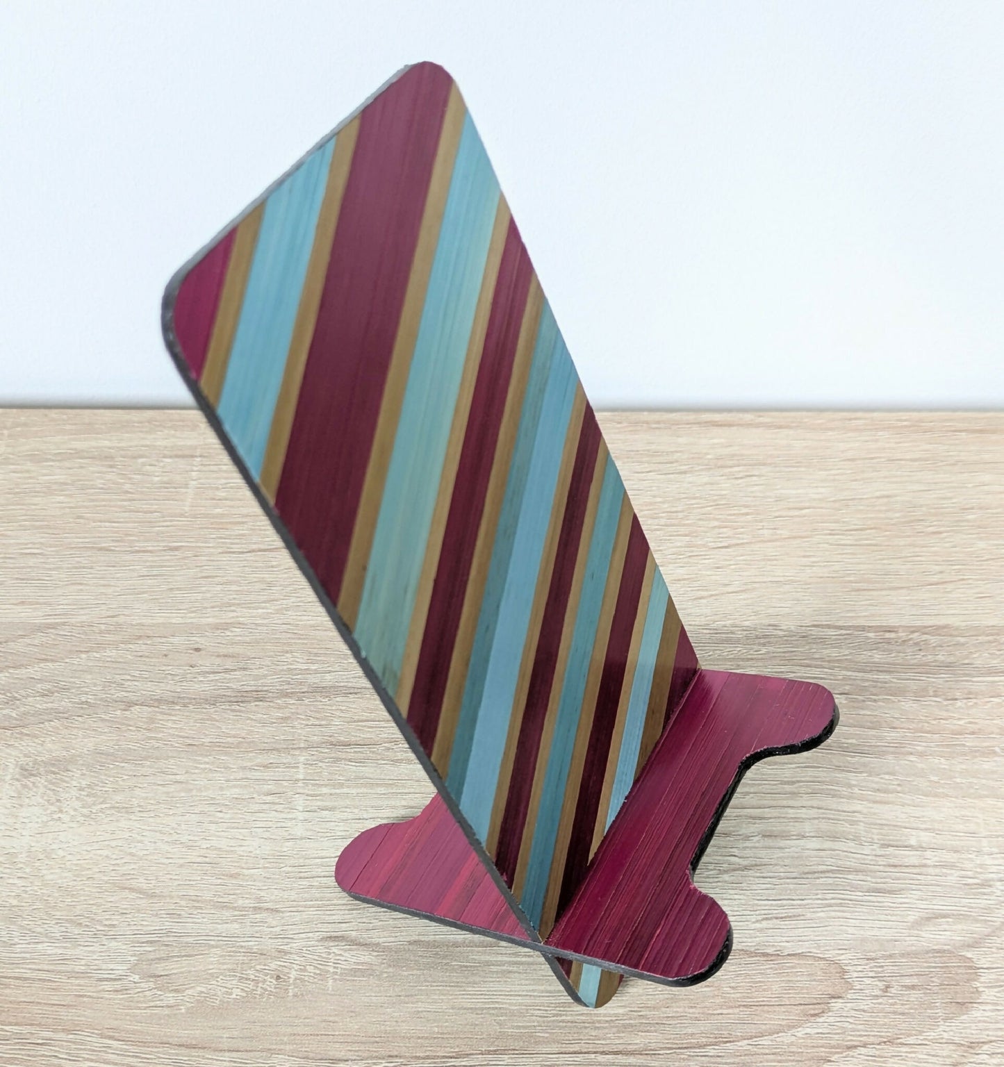 Support de téléphone incliné en bois, marqueterie rayée turquoise et bordeaux.