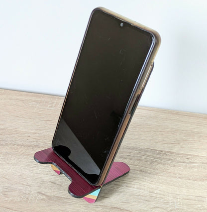 Support de téléphone avec smartphone noir posé, marqueterie rayée bordeaux et turquoise.