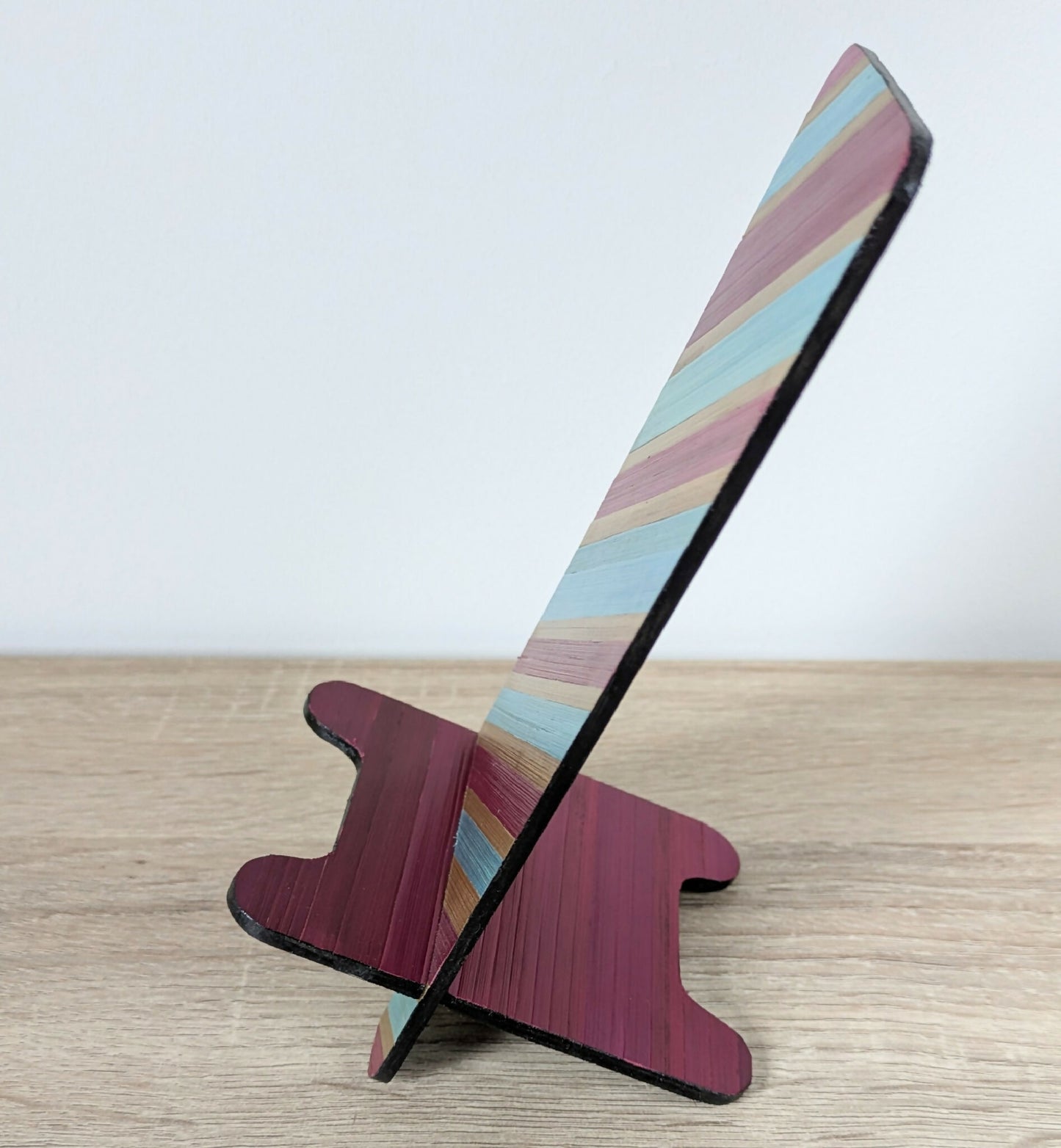 Support de téléphone en bois, marqueterie rayée bordeaux et turquoise, vue de côté.