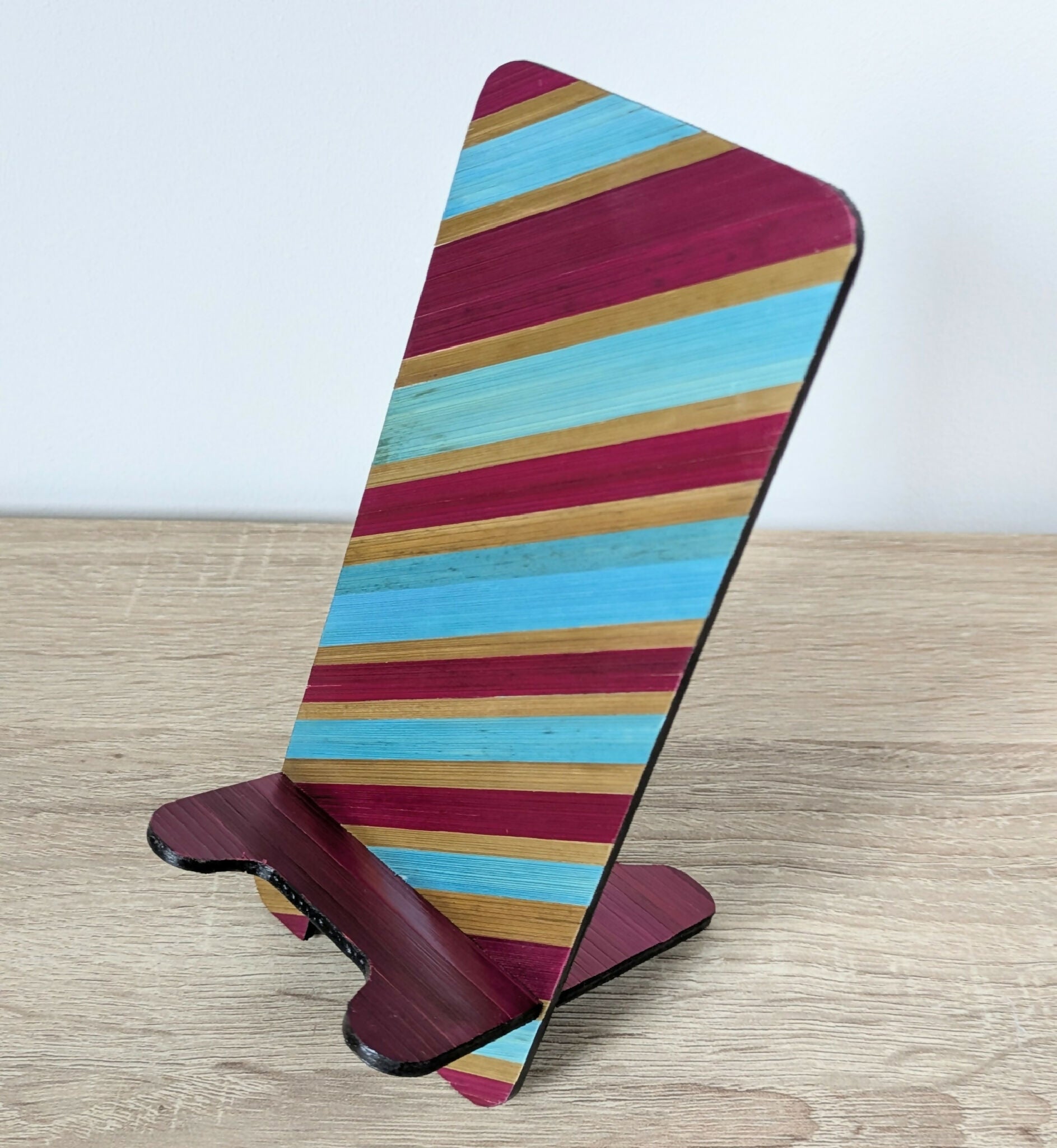 Support de téléphone en bois, marqueterie rayée bordeaux et turquoise, pieds découpés.