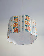 Abat-jour forme fleur en tissu bleu clair, motif floral orange et bases blanches.