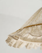 Détail du volant de l’abat-jour conique en lin et coton beige avec liseré doré