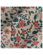 Gros plan tissu floral : fleurs et feuilles multicolores sur fond clair, coutures visibles.