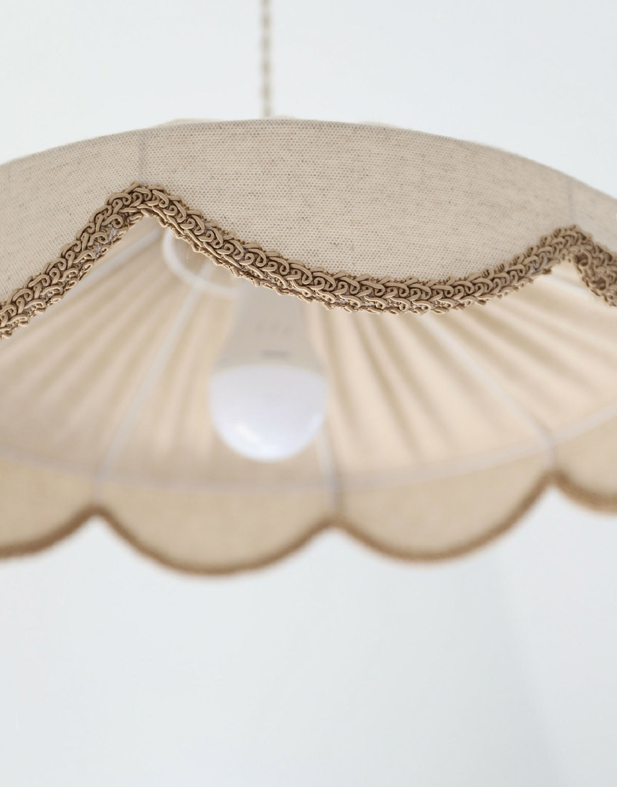 Abat-jour beige festonné avec éclairage central, bordure en tresse brune