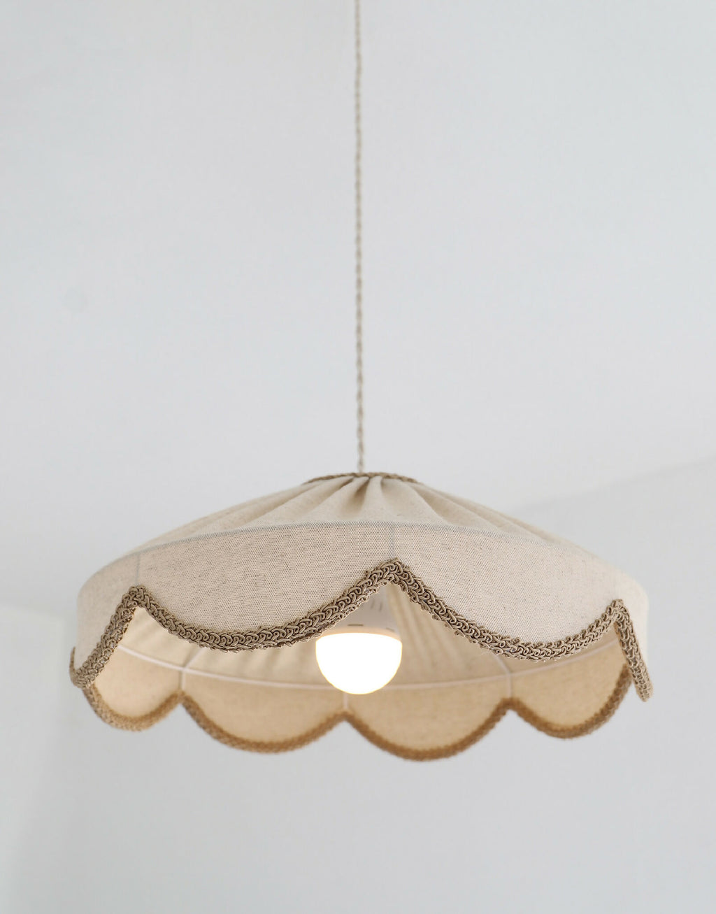 Suspension abat-jour beige festonné, tresse brune et lumière centrale