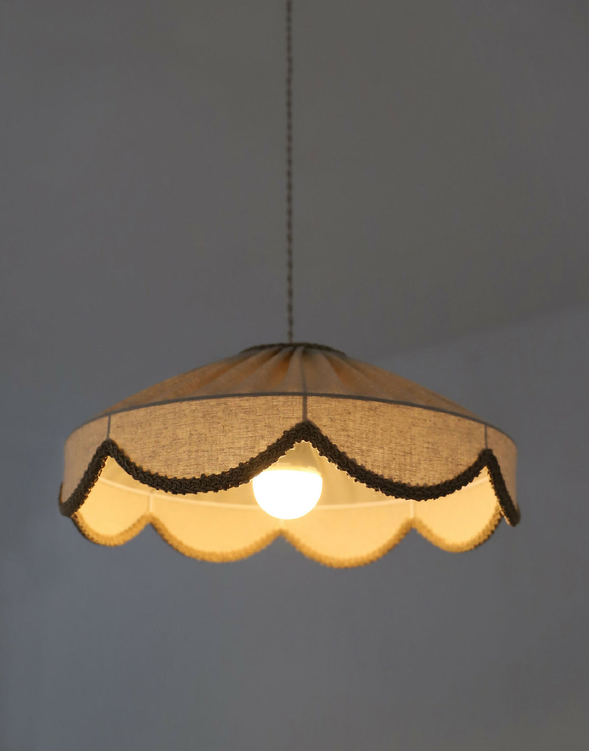 Suspension abat-jour beige festonné, bordure brun foncé et lumière diffusée