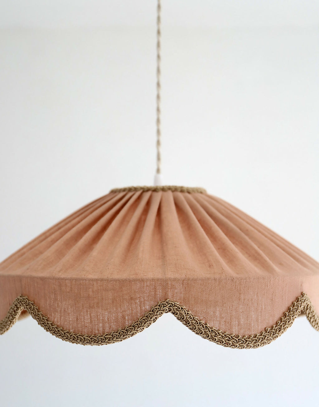 Abat-jour suspendu en lin beige rosé, forme conique froncée et bord festonné doré