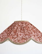 Suspension florale en tissu bordeaux, motif fleurs et bordure dorée en couronne.