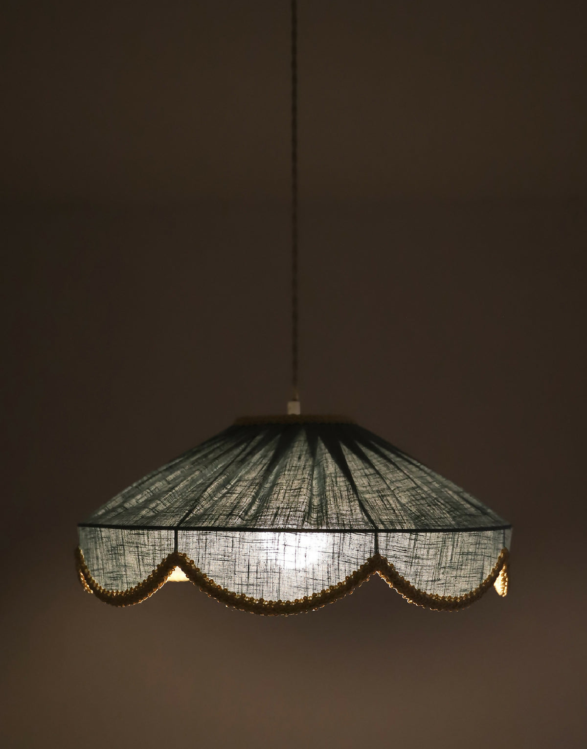 Suspension avec abat-jour sombre, bordure dorée ondulée et lumière allumée
