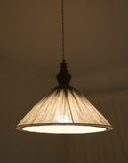 Abat-jour plissé à fines rayures avec structure intérieure, lumière allumée.