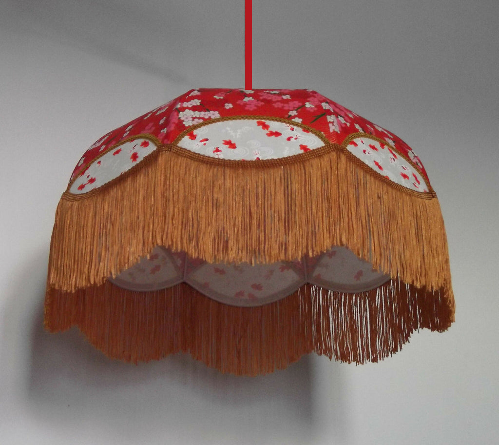Suspension en papier japonais rouge, franges dorées et motifs blancs sur l’abat-jour