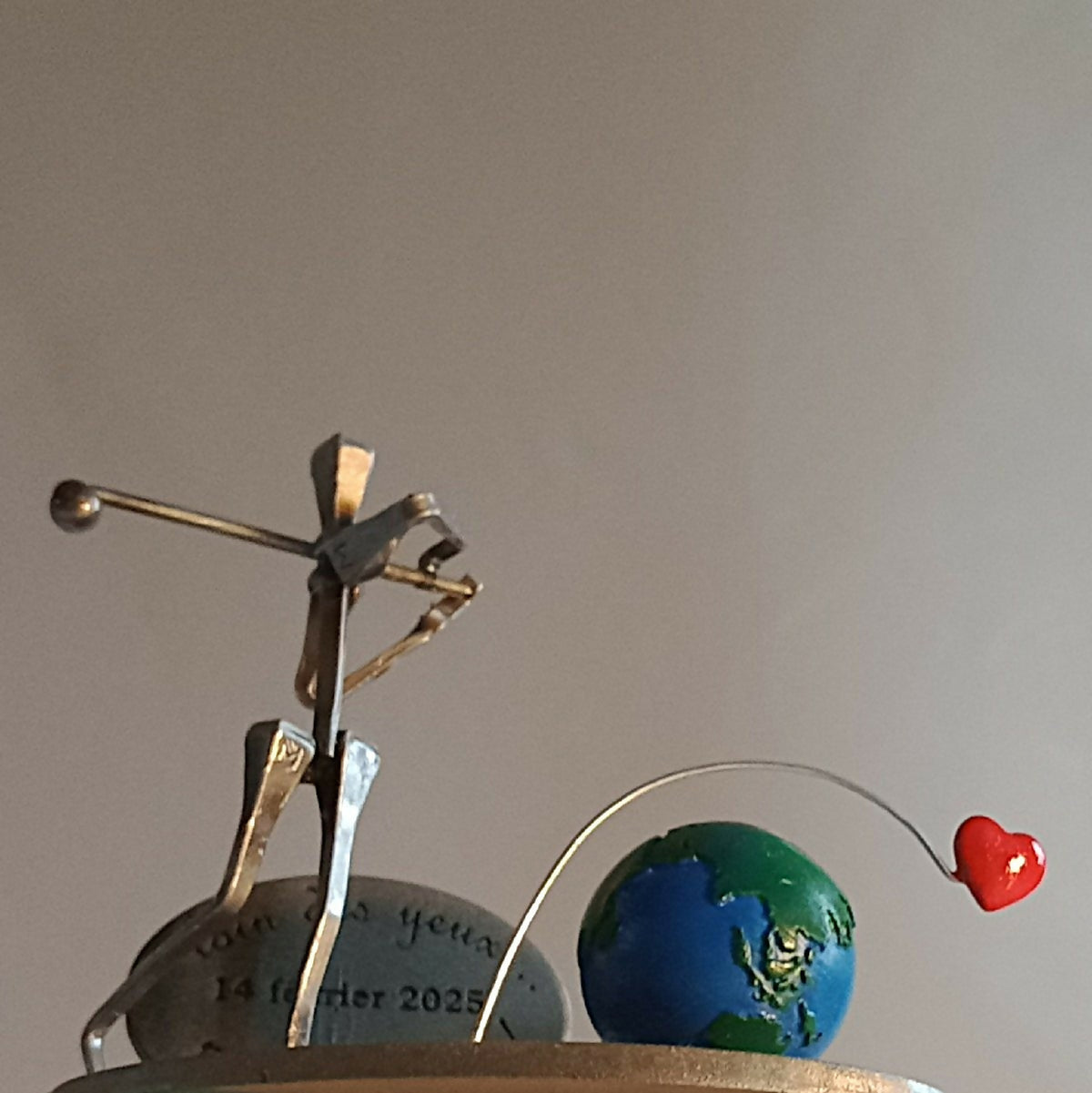 Statuette de golfeur métal doré, globe bleu-vert et cœur rouge sur socle