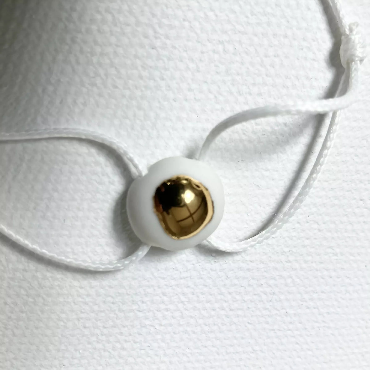 Bracelet goutte d’or : perle ronde dorée sur cordon blanc