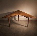 Table d’angle en bois brun, plateau cintré, structure en barreaux sous le plateau.