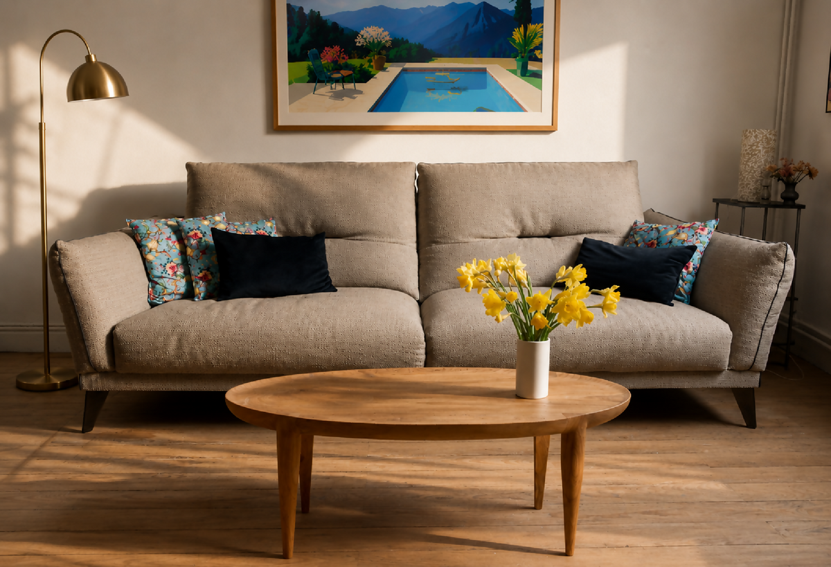 Table basse ronde en bois clair, pieds fins, plateau avec veines apparentes.