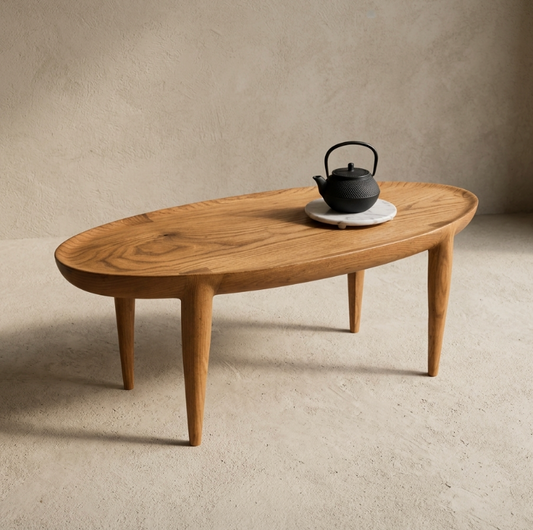 Table basse en bois au plateau ovale, pieds galbés, avec bouilloire sur un dessous de tasse.