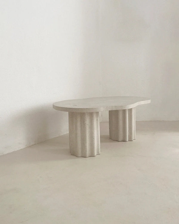 Table basse HESTIA ronde, plateau clair et pieds cylindriques cannelés.