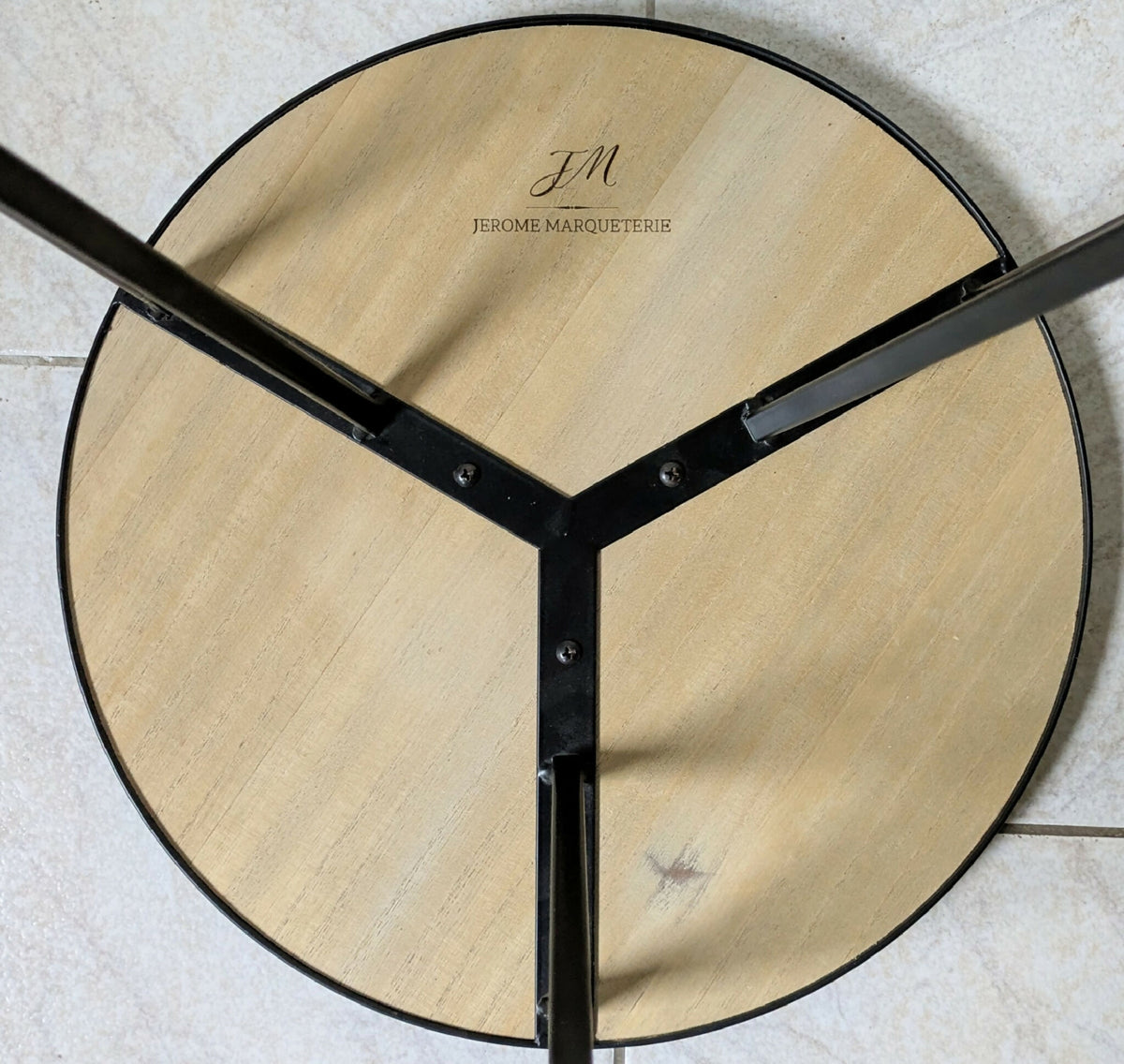 Dessous de table ronde : plateau paille dorée, piétement métal noir en X, marque