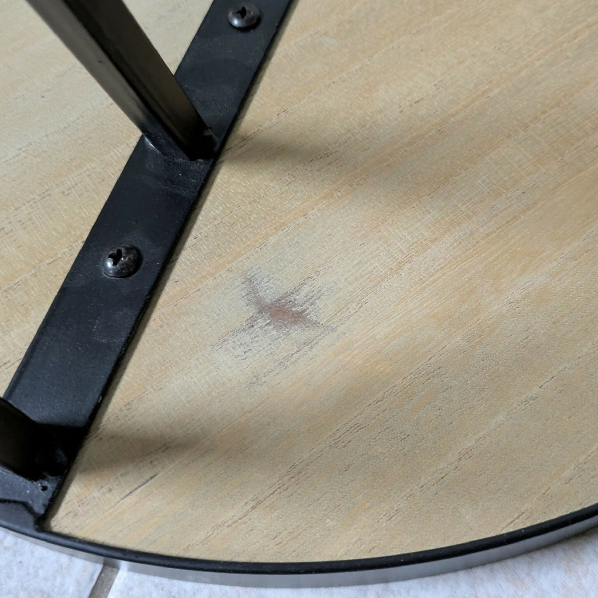 Piétement métal noir de table ronde, vis visibles, plateau paille dorée