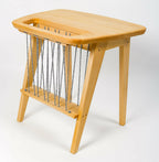 Table en bois avec cordes noires suspendues et piètement triangulaire