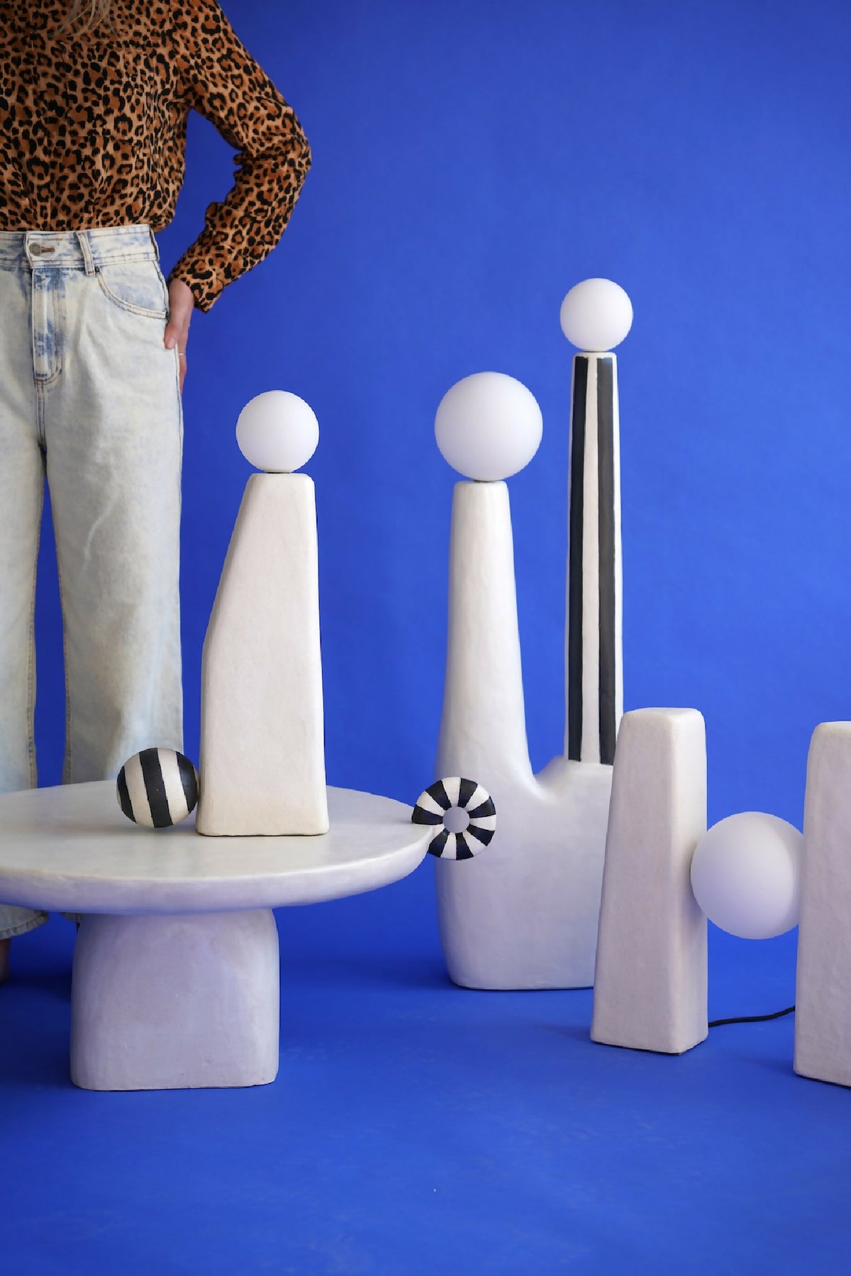 Table sculpturale avec figurines géométriques sur plateau, blanc et gris clair.