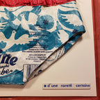 Culotte encadrée : partie imprimée bleu oiseaux et texte, avec bordure rouge à volants.