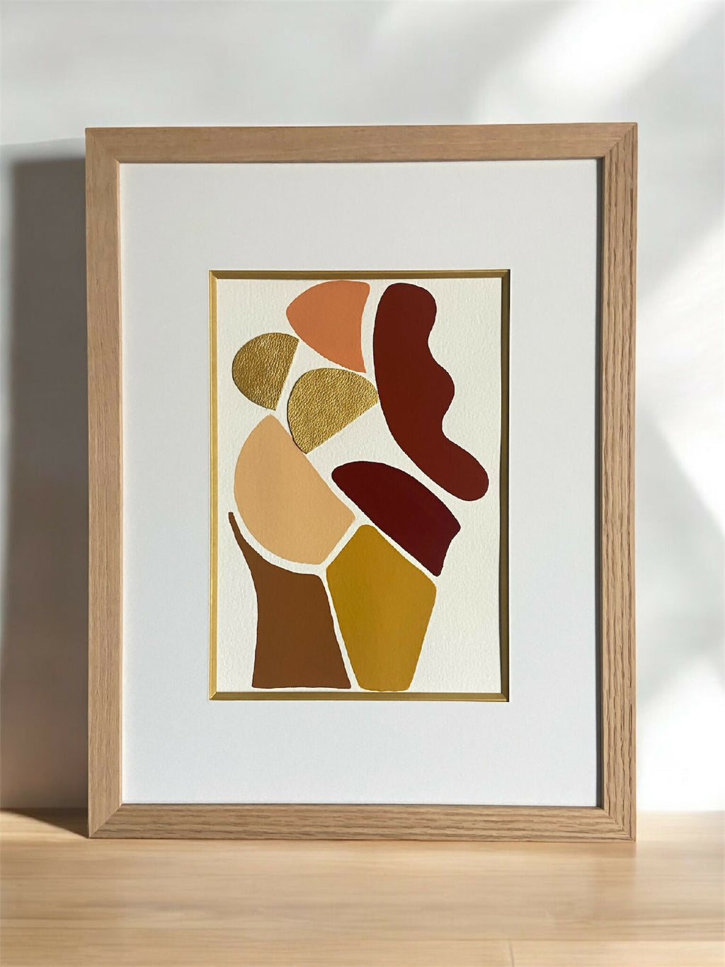 Tableau encadré, composition abstraite de silhouettes en tons ocre et brun, au centre.