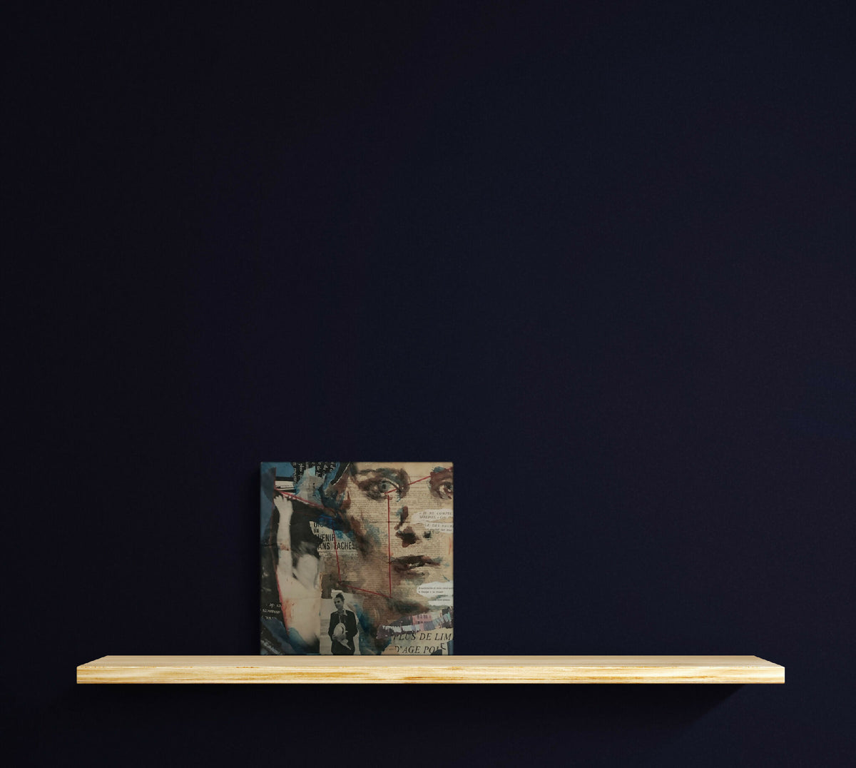 Tableau carré en collage, posé sur une étagère, tons bleus et beiges.