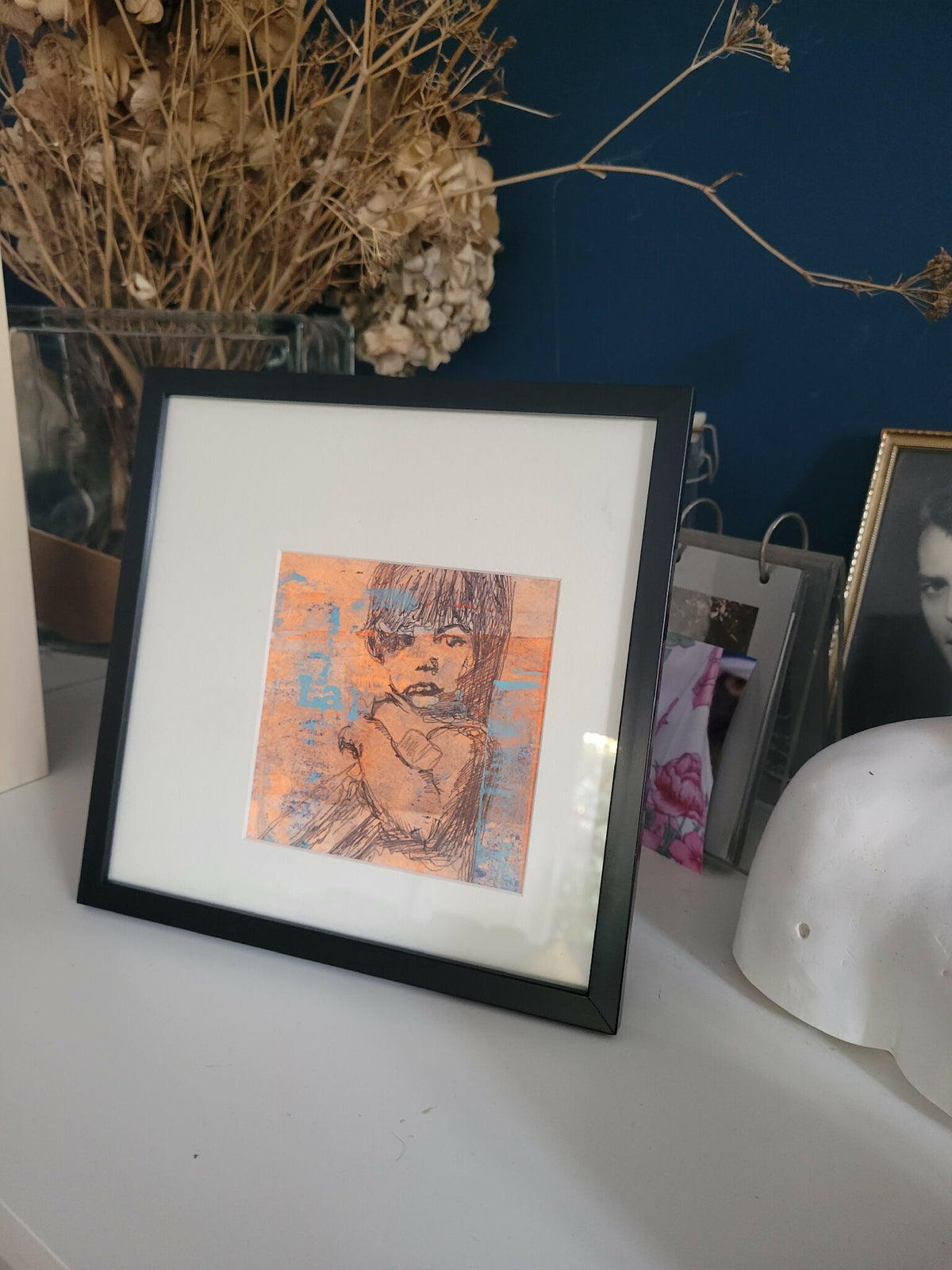 Tableau encadré posé sur un meuble, portrait stylisé orange et bleu