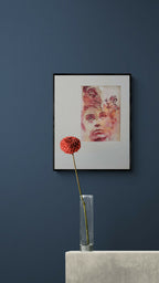 Tableau encadré noir avec portrait en teintes rouges et papier texturé à l’intérieur.