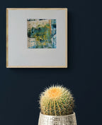 Tableau abstrait bleu-vert et jaune, cadre bois clair, affiché au mur.