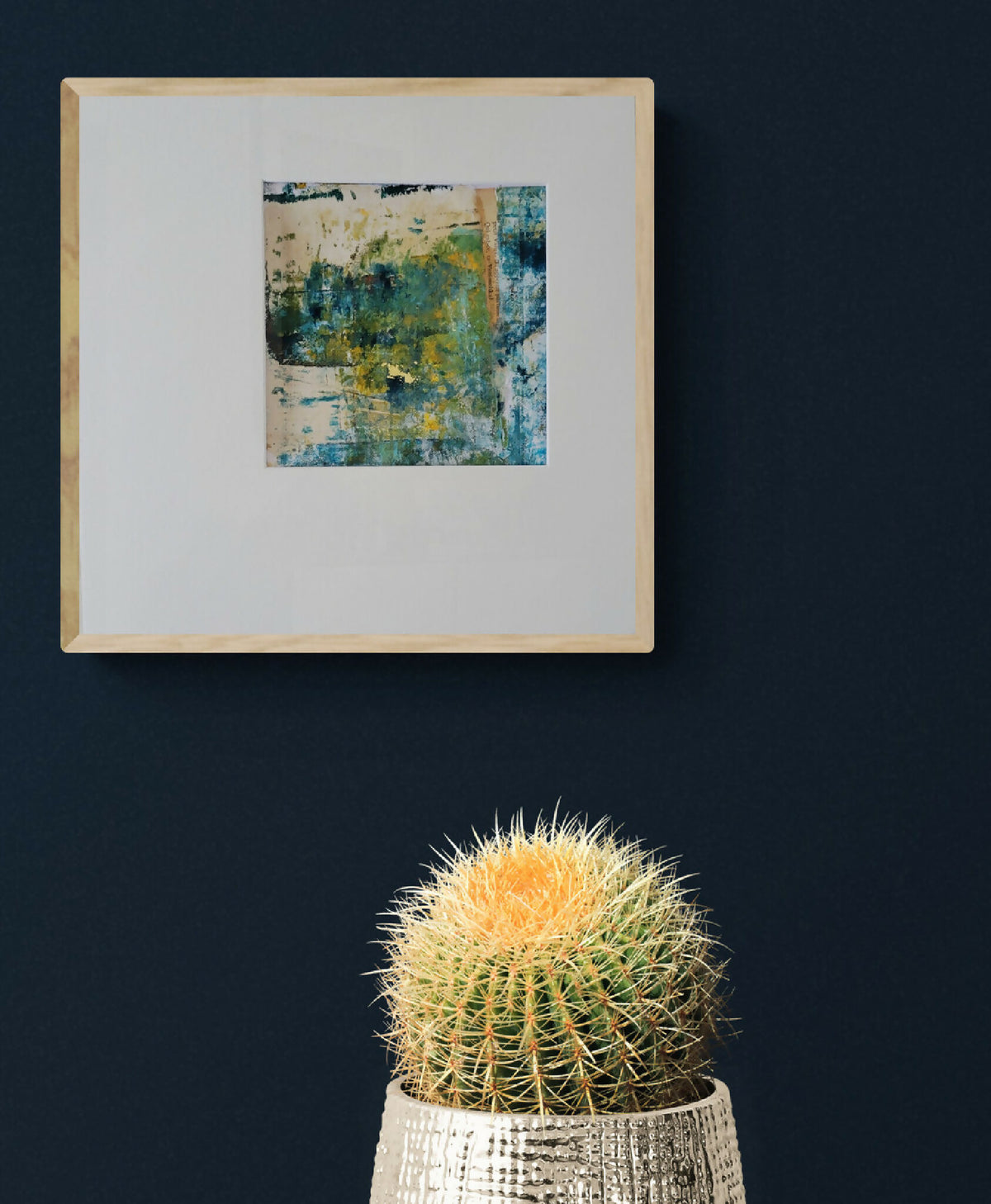 Tableau abstrait bleu-vert et jaune, cadre bois clair, affiché au mur.
