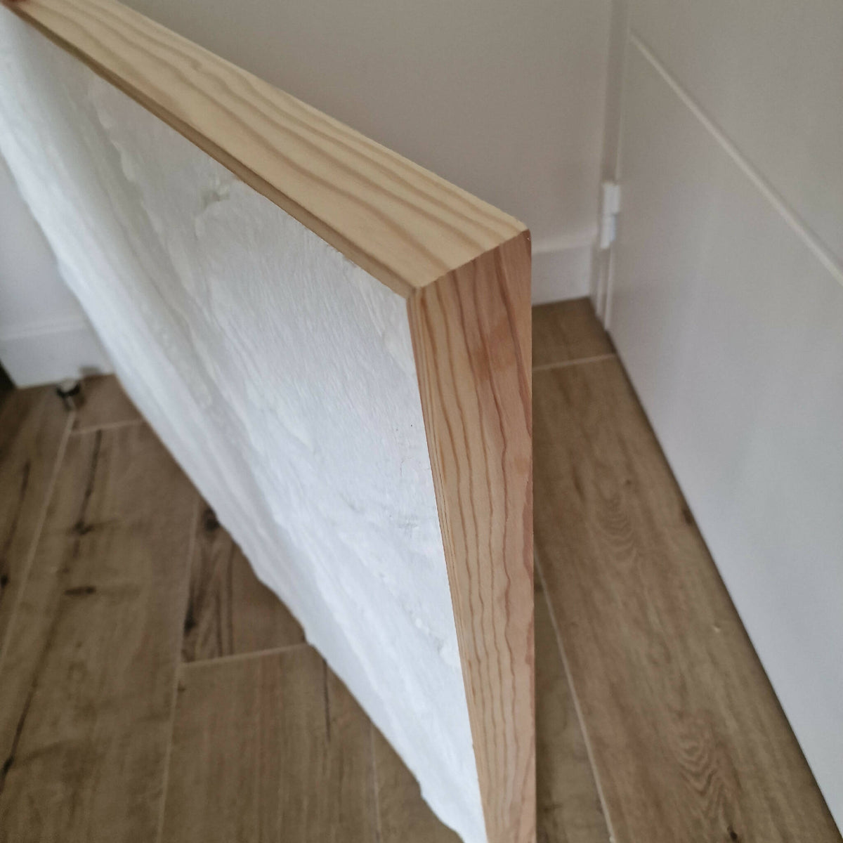 Tableau texturé blanc vue de côté, cadre en bois clair fin
