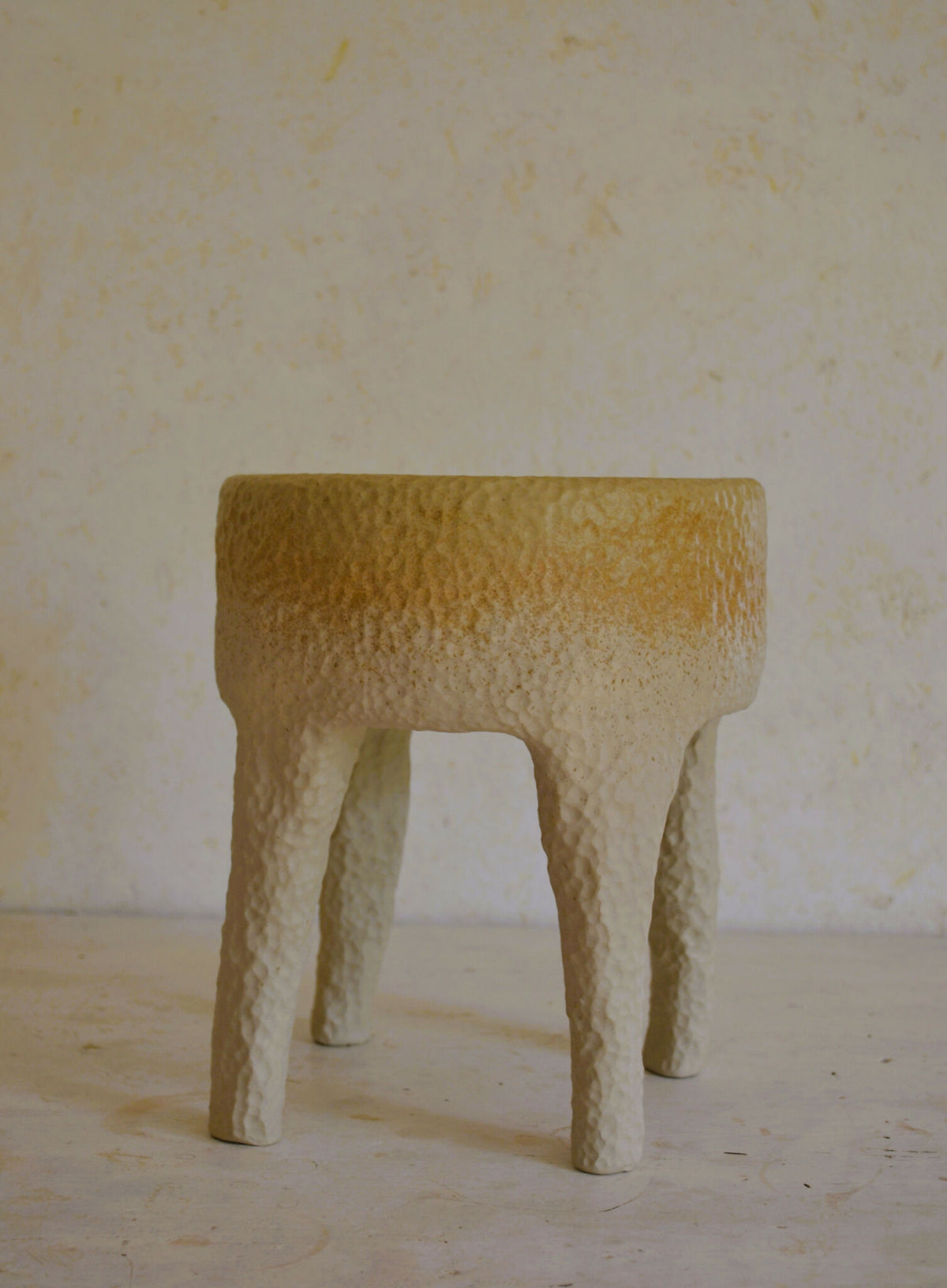 Tabouret en céramique beige texturé, plateau arrondi et pieds évasés