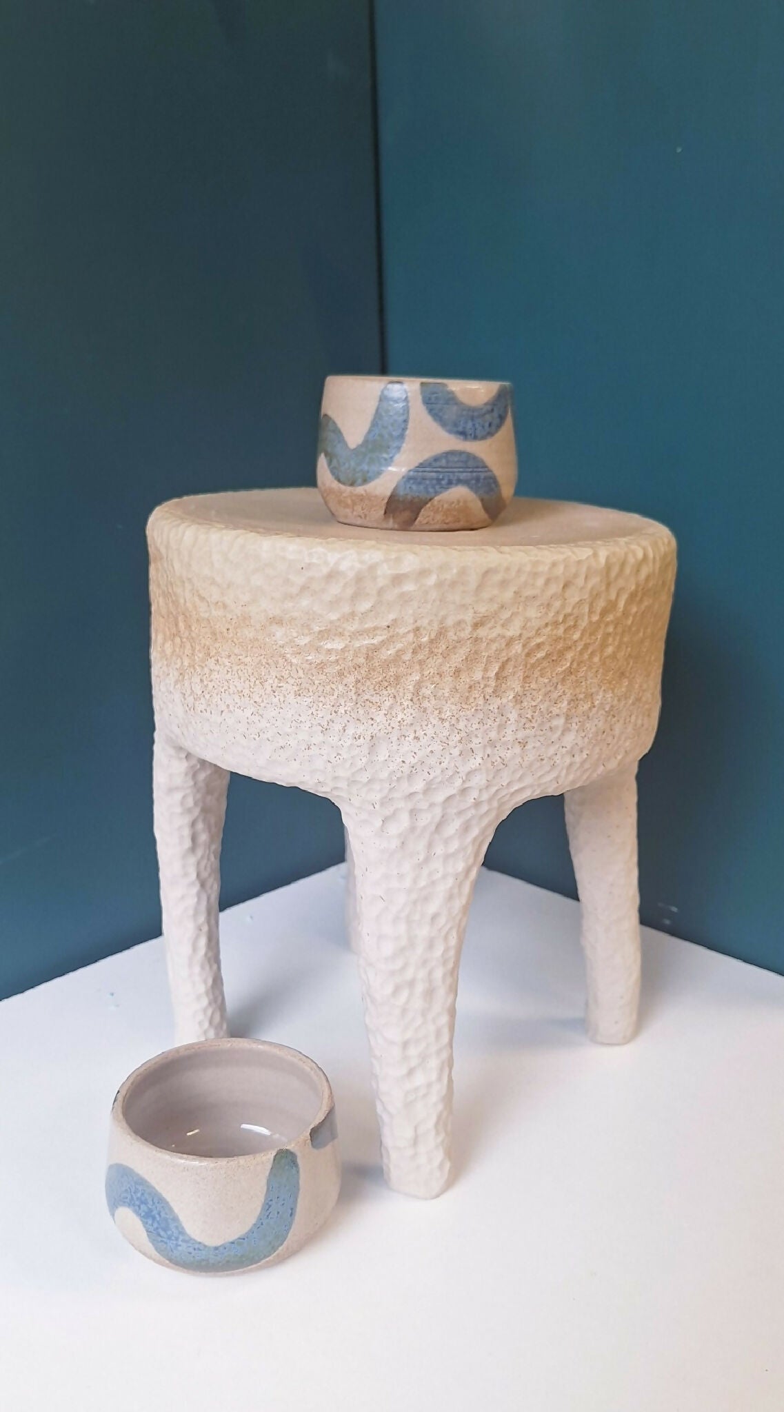 Tabouret en céramique beige texturé avec bol en céramique bleu sur le dessus