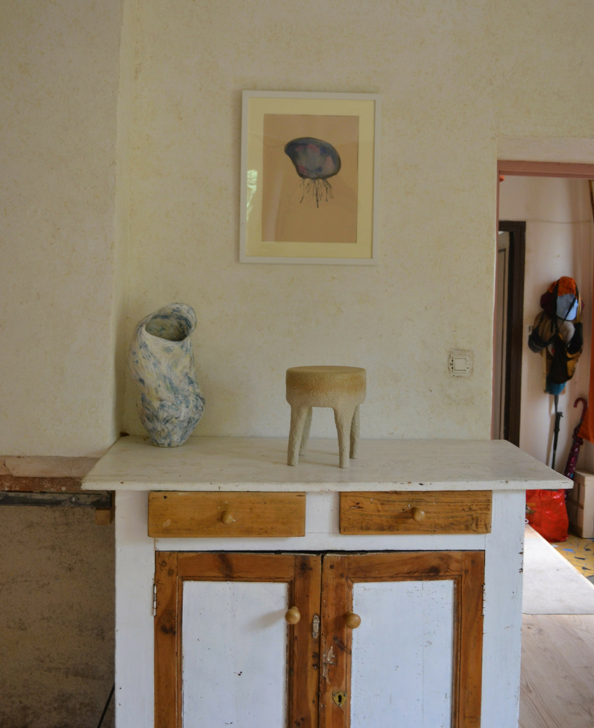 Tabouret en céramique beige, surface ronde et pieds courts, finition texturée