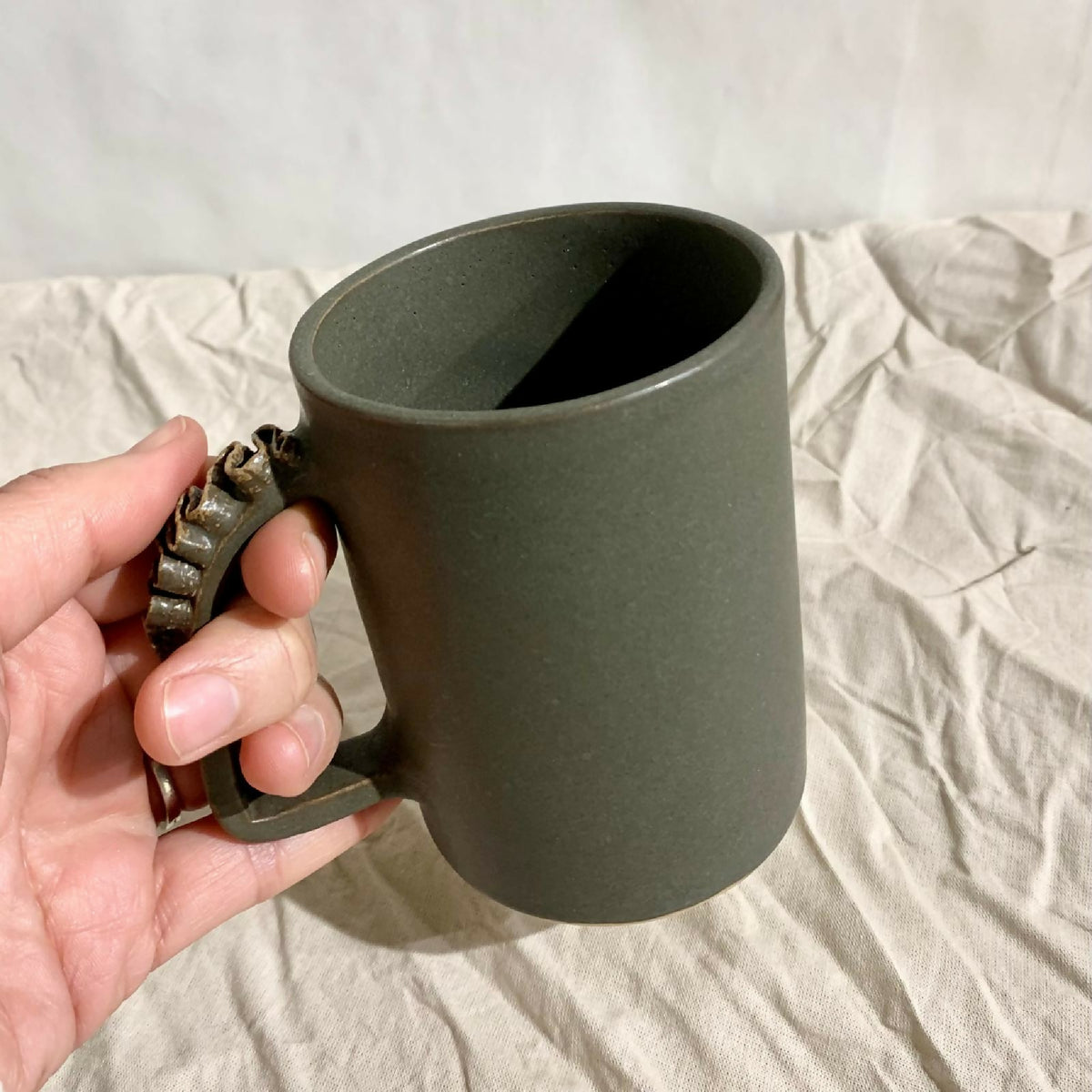 Tasse à thé kaki foncé en céramique, anse sculptée et prise en main.