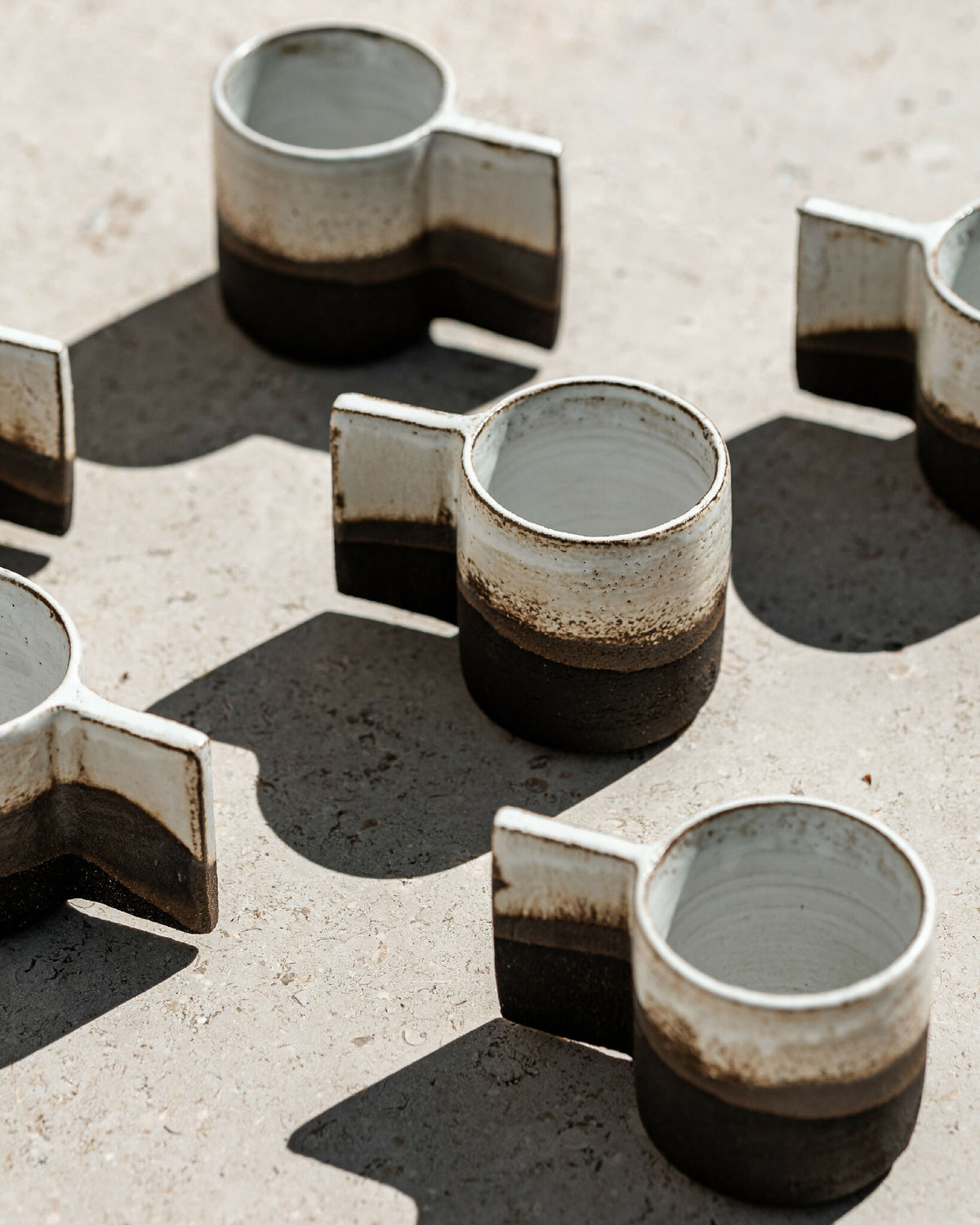 Lot de tasses expresso Luna en céramique, base noire et bord clair texturé.