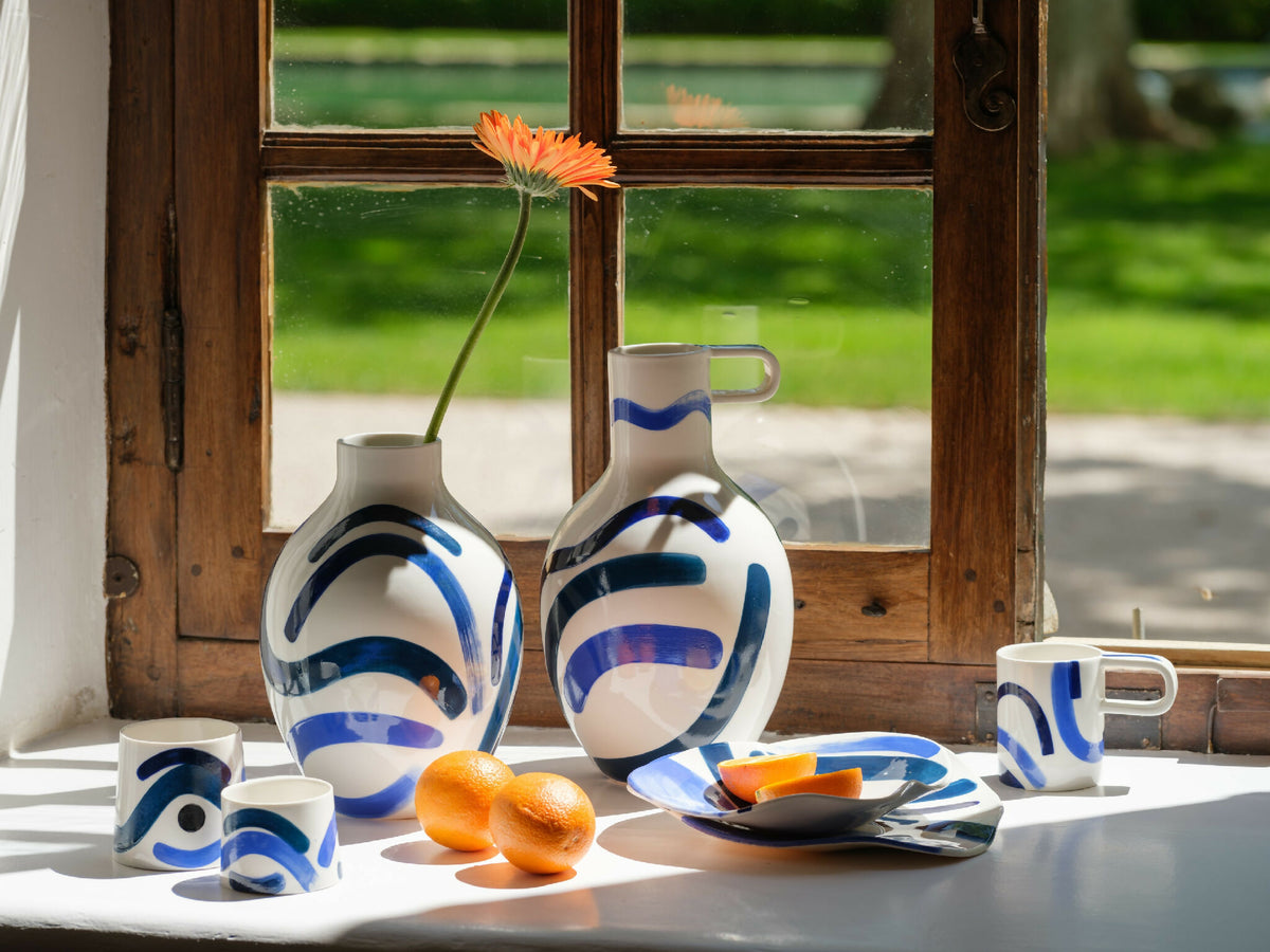 Ensemble de petites tasses trapèzes blanches à motifs bleus, poignées visibles.