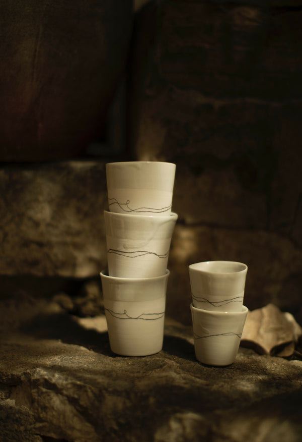 Trois petites tasses en porcelaine à liseré, décor de lignes, teinte crème.